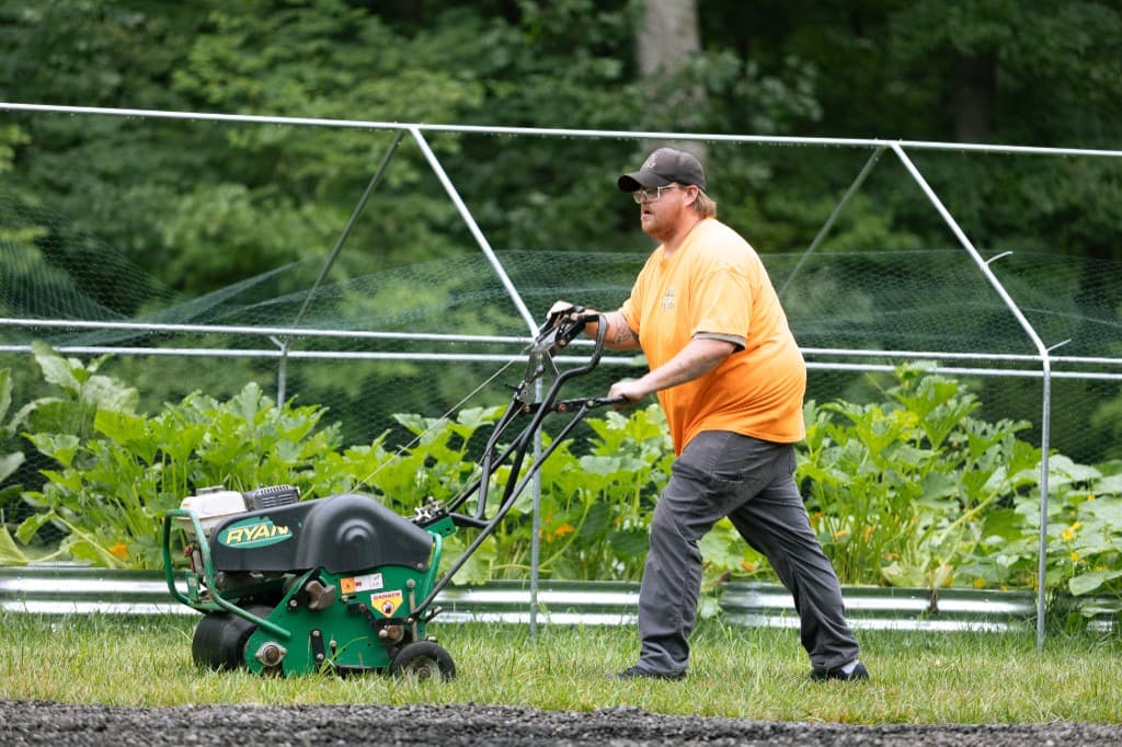 Simply Turf technician running a walk-behind core aerator