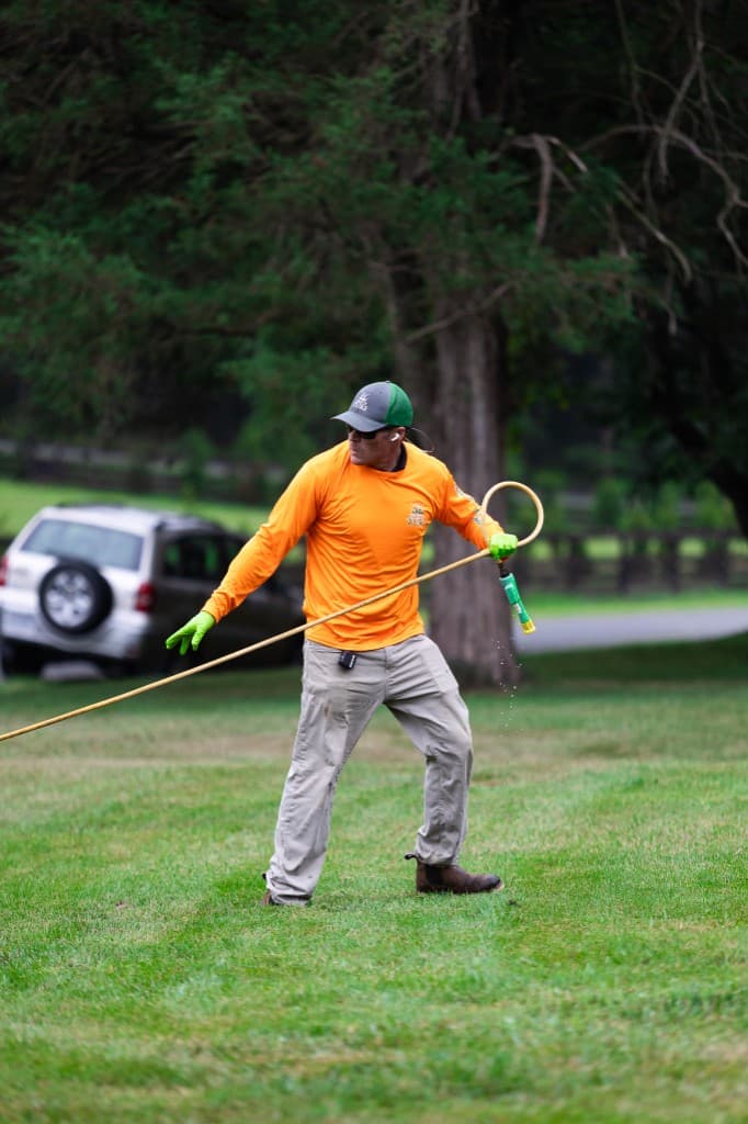 Simply Turf technician treating a lawn with a spray wand