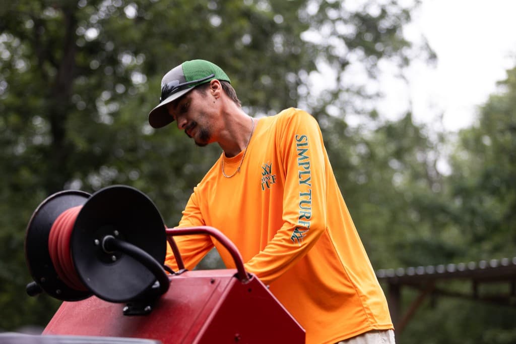 Simply Turf technician in uniform preparing spray equipment on his rig